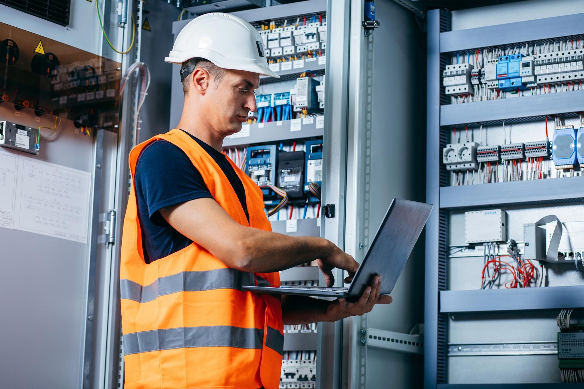 Ingenieur prüft Steuerungskasten mit Laptop | Kabelbaum