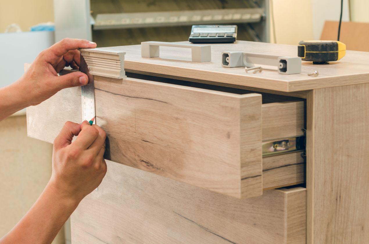 möbelbau berlin im Detail – Hand misst präzise eine Holzschublade für individuelle Möbelanfertigung