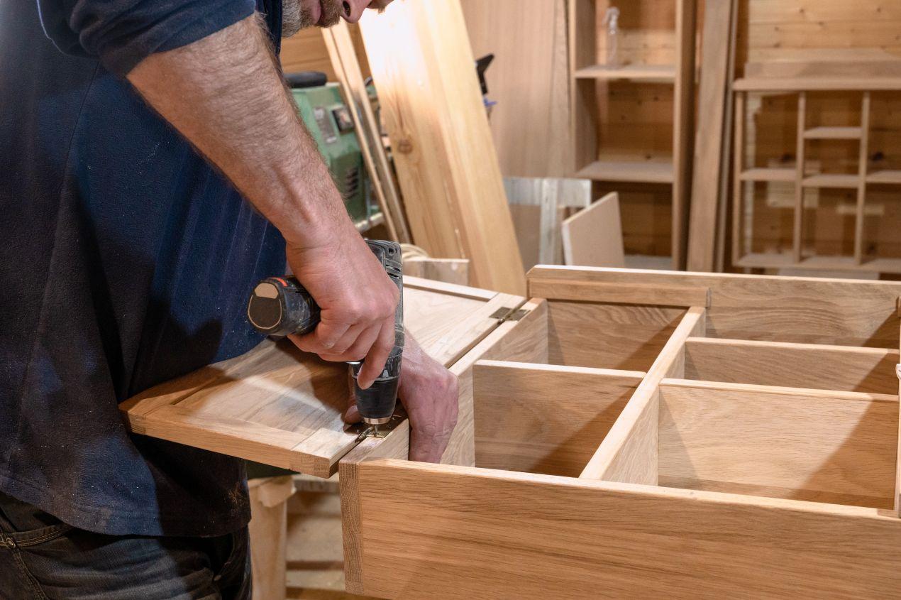 möbelbau berlin in der Werkstatt – Handwerker verschraubt Holzelement für maßgefertigtes Möbelstück