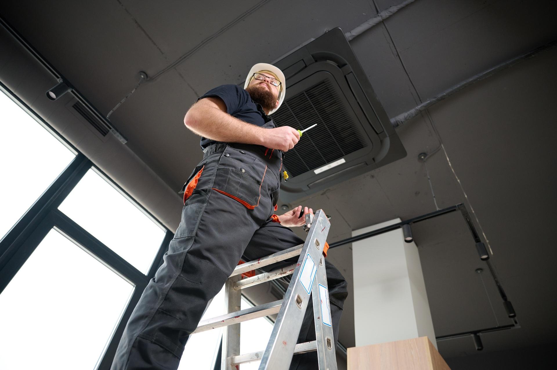 Handwerker mit Helm bei Wartung an Decke | Arbeiten in kontaminierten Bereichen