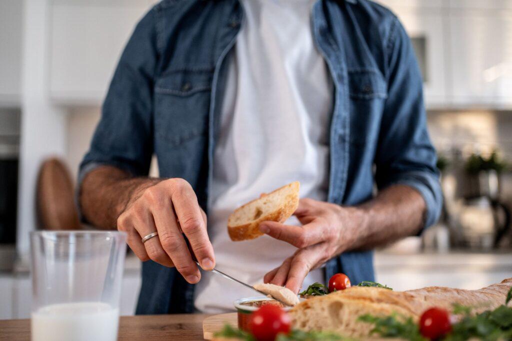 Mann schneidet Brot in moderner Küche